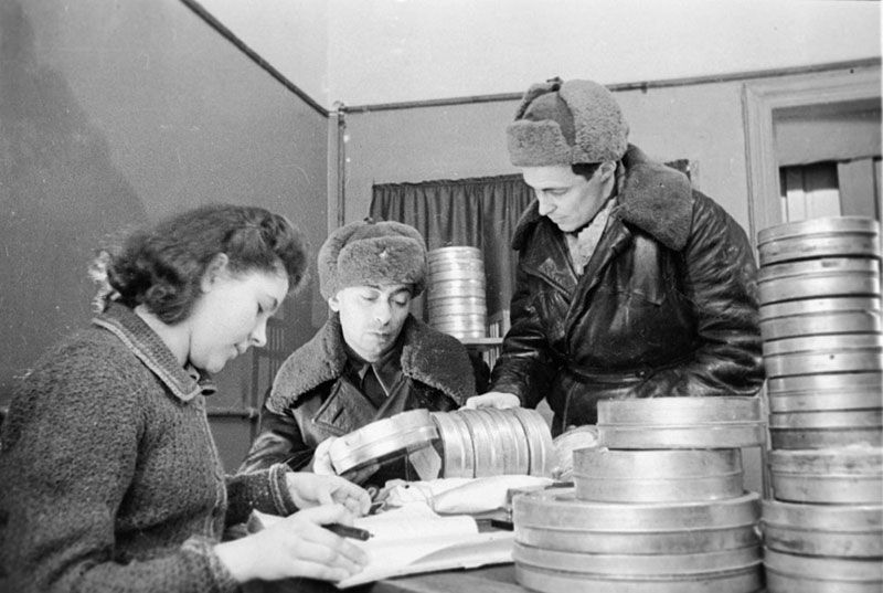 Прибывшие с фронта кинооператоры Р.Б. Гиков и И.С. Гутман сдают работнице ЦСДФ 1943.